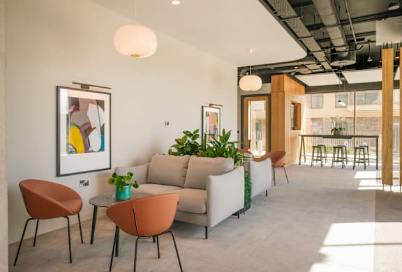A living room with a couch, chairs, and a potted plant.