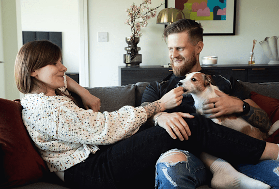 A man and woman sitting on a couch with a dog.