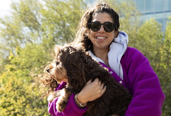 A woman in a purple jacket holding a dog.