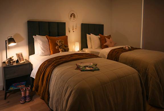 A cozy bedroom with two beds and a nightstand with a lamp.