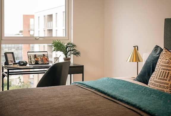 A bedroom with a bed, desk, and chair.