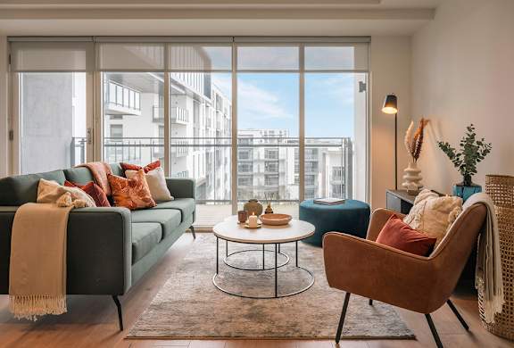 A living room with a couch, chair, and table with a view of the city.