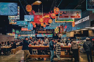 A busy sushi restaurant with people dining and a sign that says "Market Sushi".