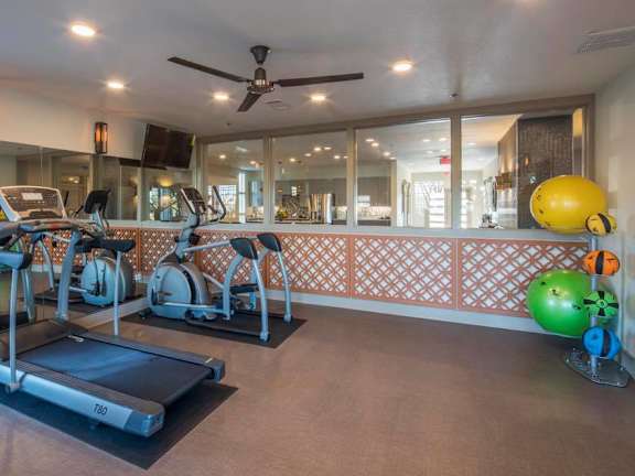 A gym with treadmills, exercise bikes, and a fan.