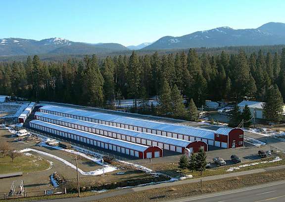 A large building with a red roof is surrounded by a forest.