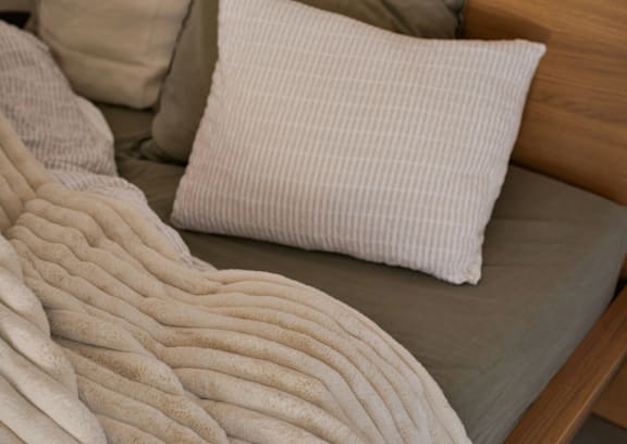 A white pillow with a striped pattern is on a beige couch.