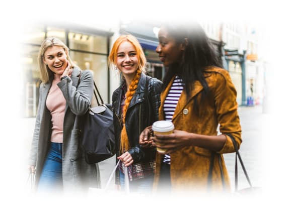 three women walking down the street and talking