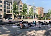 Thumbnail 3 of 6 - A group of people are practicing yoga on the street.
