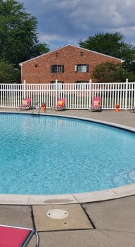 a pool with orange chairs and a white fence around it