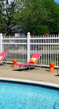 a swimming pool with chairs and an umbrella next to it