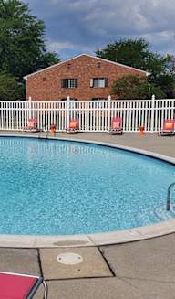 a pool with orange chairs and a white fence around it