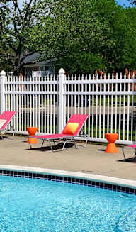 a swimming pool with chairs and an umbrella next to it