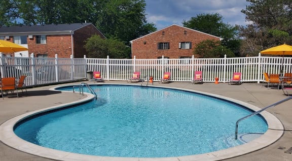a pool with orange chairs and a white fence around it