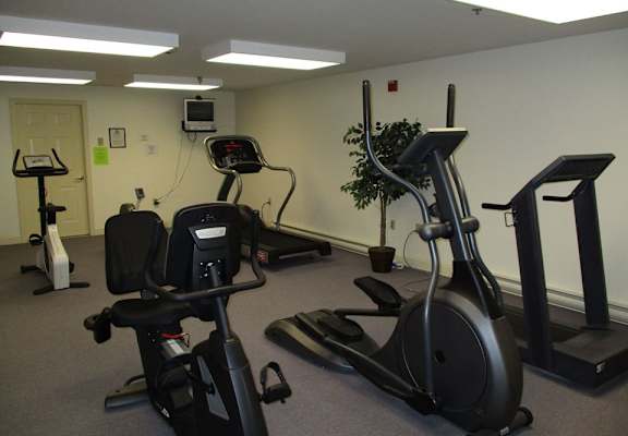 A gym with a treadmill, elliptical trainer, and stationary bike.