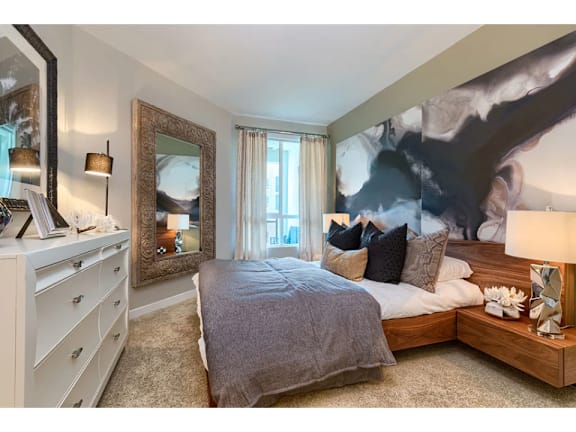 A bedroom with a large bed, a dresser, and a large painting on the wall.