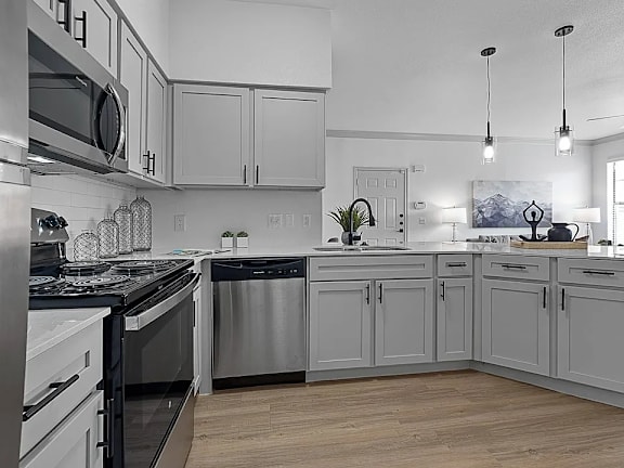 A modern kitchen with stainless steel appliances and wooden floors.