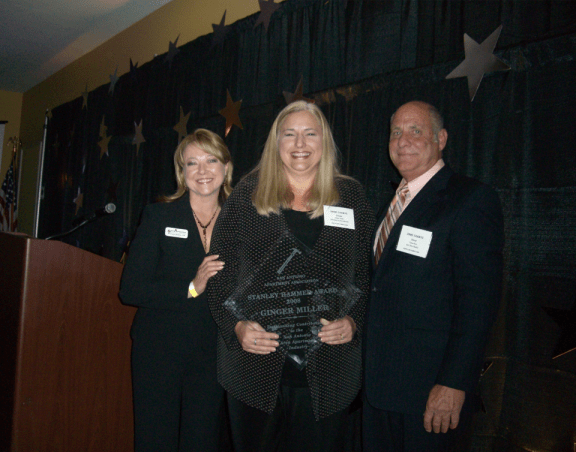 three people standing next to each other holding an award