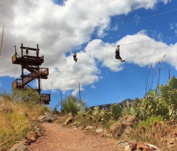 people on a zip line in the air on a cloudy sky