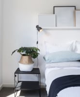 a bedroom with white walls and a white bed with blue bedding and a black nightstand