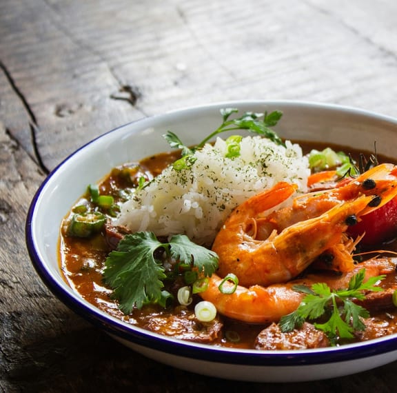 a bowl of soup with shrimp and rice and vegetables