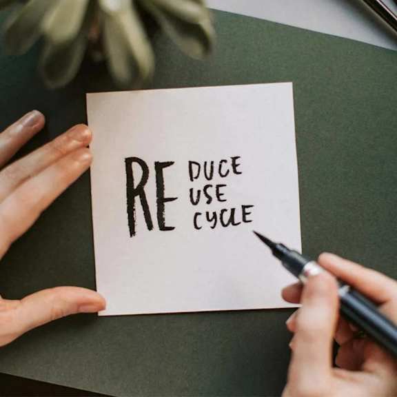 a hand writing a piece of paper with the words re use cube on it