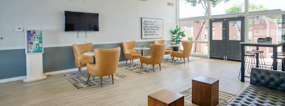 A living room with a television, chairs, and a ceiling fan. at Connect on Missour Apartments, Phoenix 85015