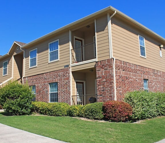A two-story apartment building with a brick facade and a balcony on the second floor.