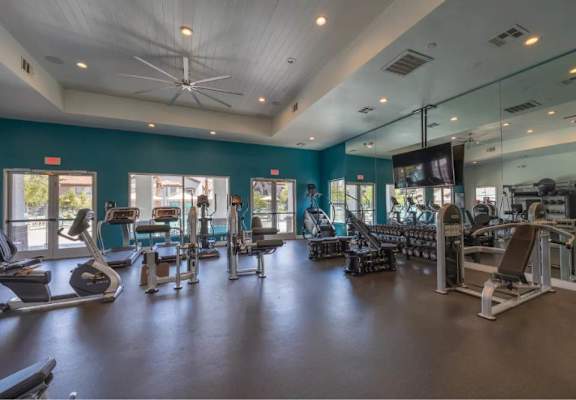 A spacious gym with a variety of equipment and a ceiling fan.