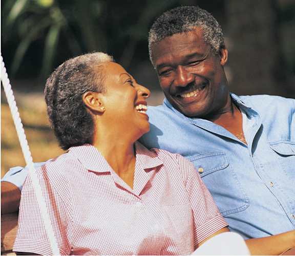 An older couple laughing together on a swing.