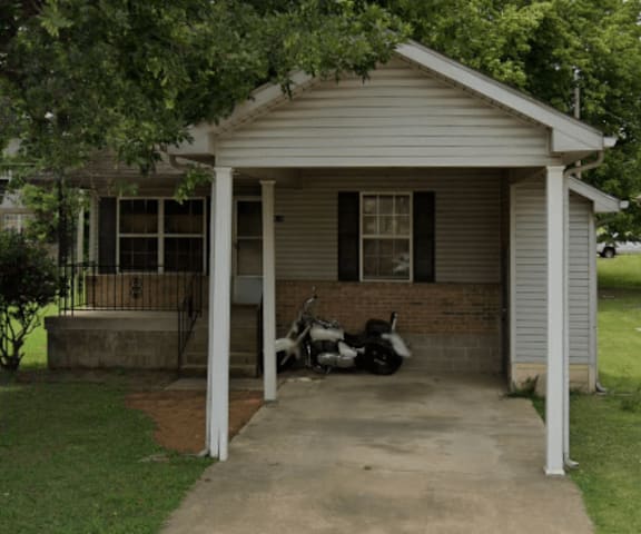 A small house with a covered porch and a motorcycle parked in front.