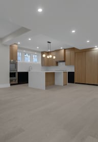 an open kitchen and living room with white walls and wood flooring