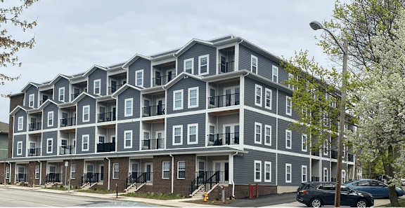 A large grey apartment building with multiple balconies and doors.