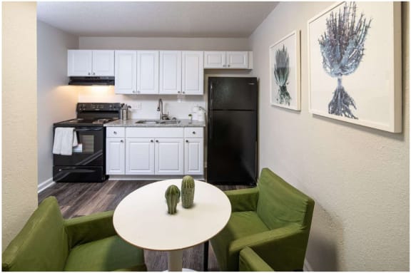 a kitchen with white cabinets and a white table and green chairs at Viceroy Apartments, Durham , 27707