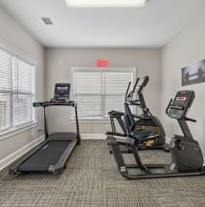 A gym room with treadmills and elliptical machines.