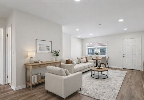 A living room with a white couch, a coffee table, and a television.