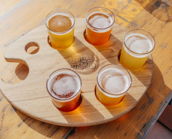 a flight of beer on a cutting board on a wooden table