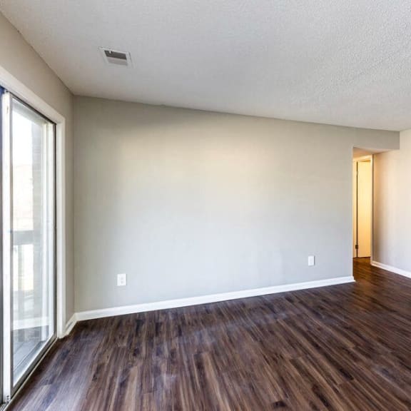 an empty living room with wood flooring and a sliding glass door
