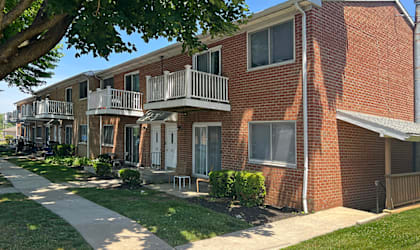 A red brick apartment building with a white railing on the balconies.