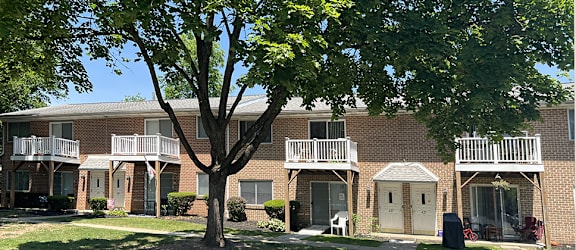 A tree in front of a brick building with a white door.