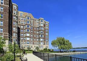 Alden Towers apartment building sitting alongside the Detroit River with sidewalk paths.
