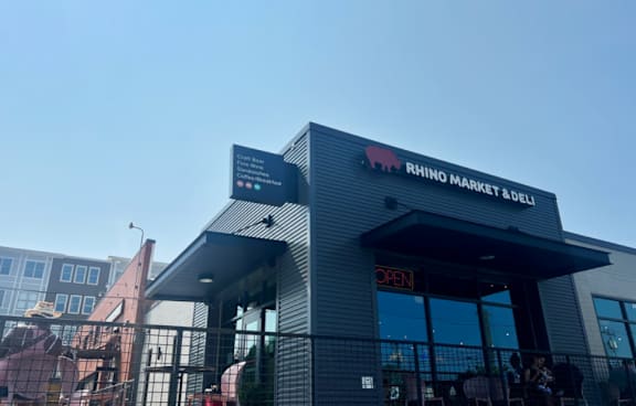 A Rhino Market and Deli storefront with a clear blue sky in the background.