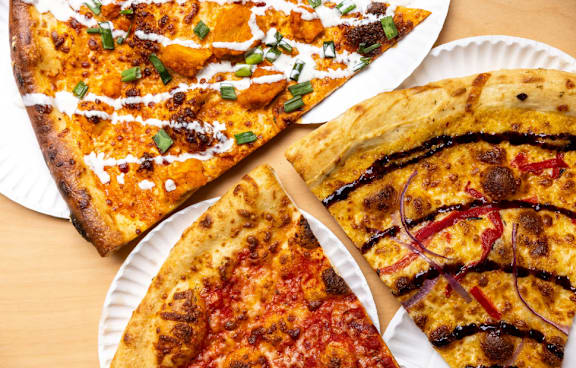 Three different types of pizza on white paper plates.