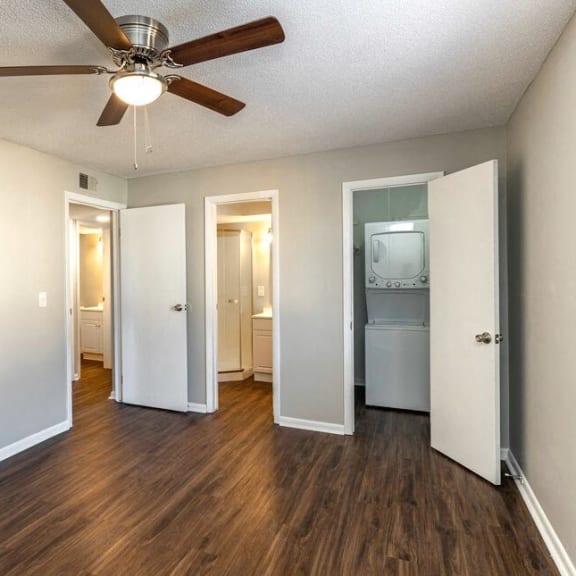 an empty living room with a ceiling fan and a laundry room