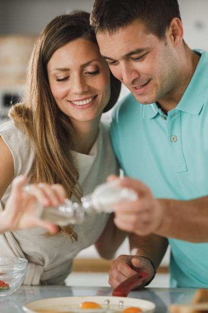 A man and woman are preparing food together in a kitchen.
