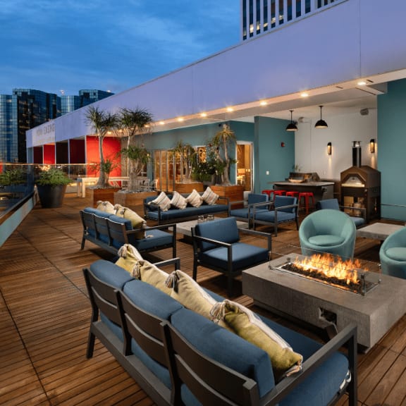 an outdoor lounge with couches and chairs and a fire pit