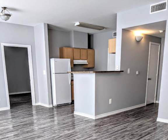 an empty room with a kitchen and a refrigerator