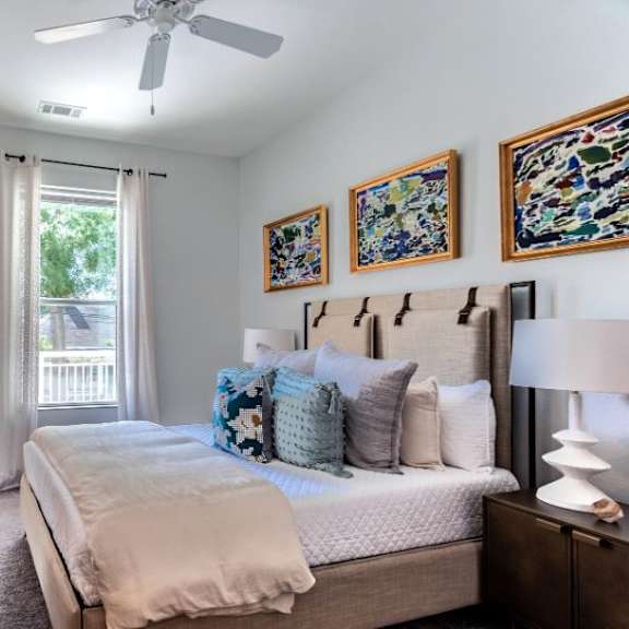A bedroom with a large bed, a dresser, and a ceiling fan.