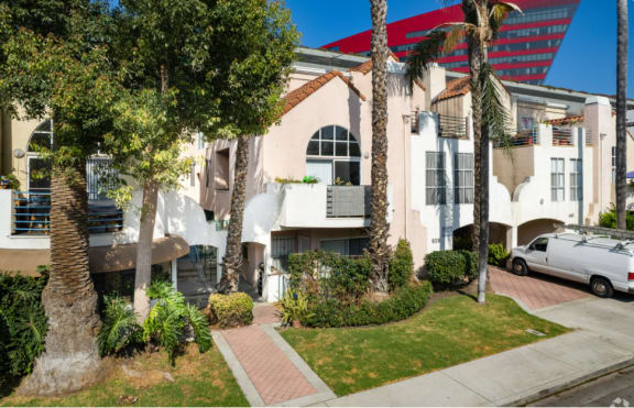 the exterior of a building with palm trees and a parking lot