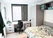 Thumbnail 1 of 8 - a bedroom with a bed and a desk with a chair
