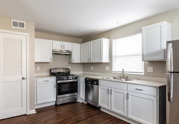an empty kitchen with white cabinets and stainless steel appliances